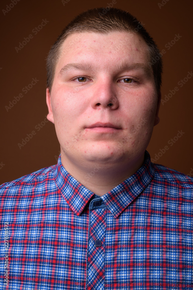 Obraz premium Studio shot of overweight young man against brown background