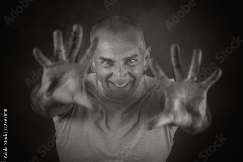 A man, 50Y old, is showing palms toward the observer. Black background, smoke. photo