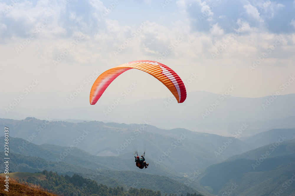 One paraglider fly over a mountain valley on a sunny summer day. Paragliding in the Carpathians in the summer. One paraglider fly over a mountain valley on a sunny summer day. Paragliding in the Carpathians in the summer.