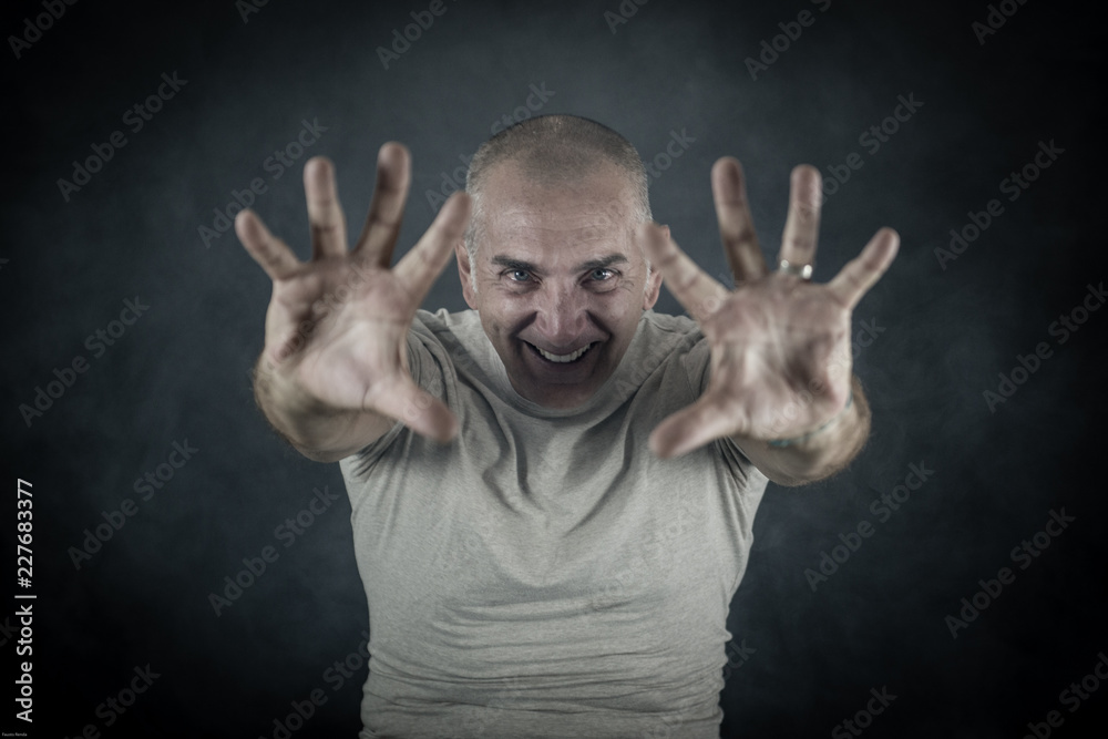 A man, 50Y old, is showing palms toward the observer. Black background, smoke. A man, 50Y old, is showing palms toward the observer. Black background, smoke.