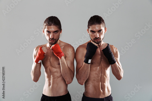 Portrait of a two confident muscular shirtless twin brothers