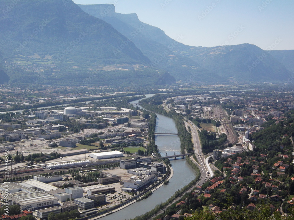 Die französische Stadt Grenoble. Ausblick nach Osten von der Bastille, man erkennt   im Zusammenfluss von Isere und Drac ein ringförmiges Gebäude - das Synchrotron ESRF.
