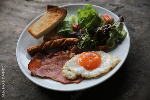 English breakfast  fried egg, ham,sausage, bacon,salad and toast on wood background in mystic light
