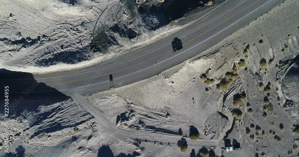 Aerial senital drone scene of eroded white rocky landscape crossed by road in sunset. Flying with top view car traveling by the route. San Juan Province, Argentina