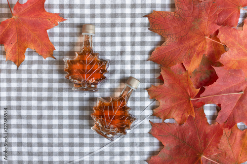 Maple syrup in a bottle in a shape of maple leaf. Red maple leaf background. photo