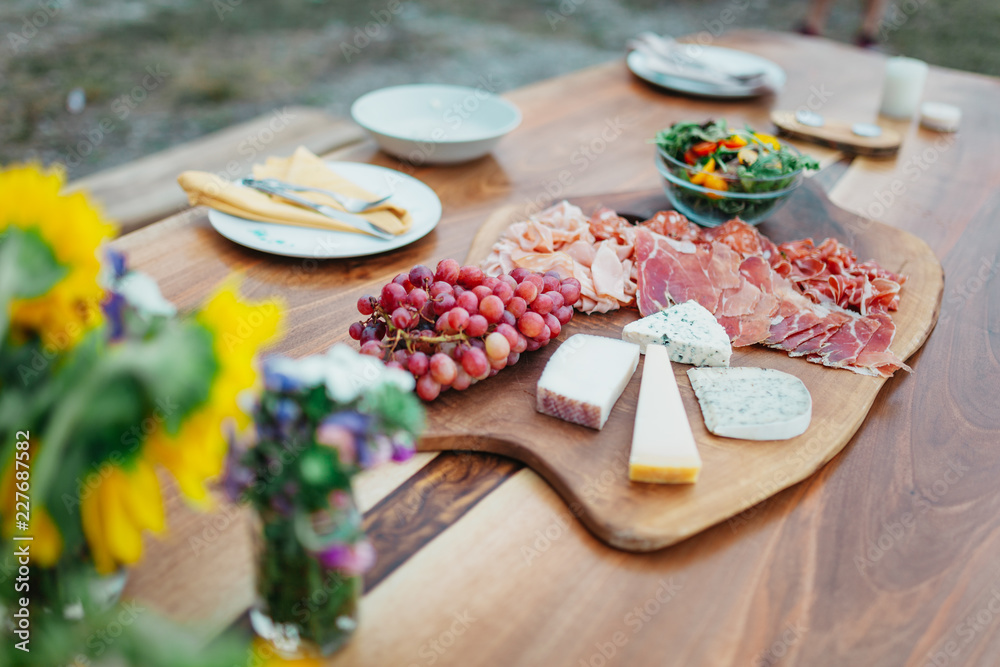 Cheese plate with grapes on a wooden table in the garden