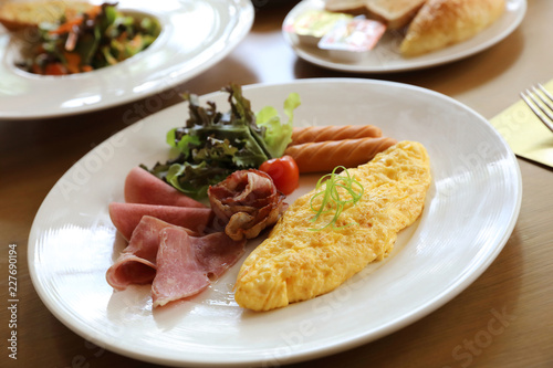 Breakfast set Omelette with sausage bacon and salad on wood background