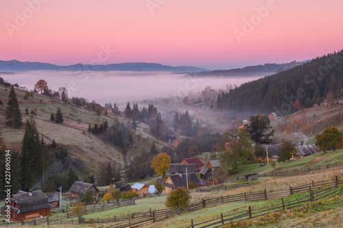 Small village in the mountains during autumn at sunrise with fog