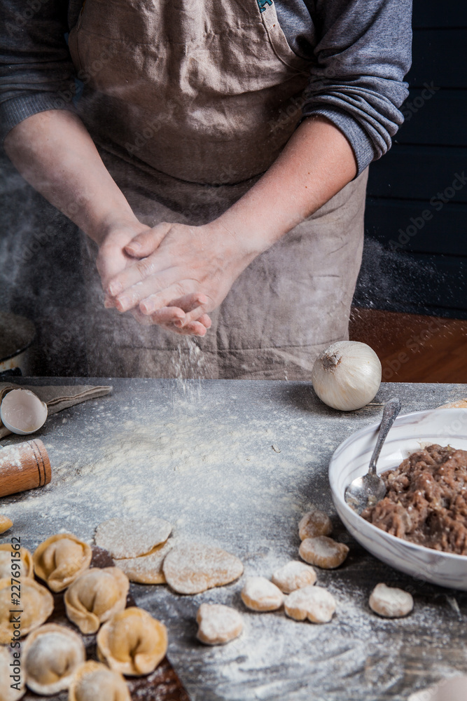 Hands of the girl prepare dumplings on a wooden table Hands of the girl prepare dumplings on a wooden table