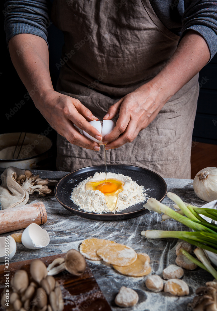 Hands of the girl prepare dumplings on a wooden table