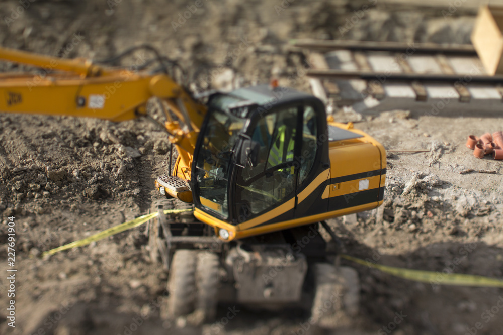 Tilt-shift capture of an excavator in a construction site. Tilt-shift capture of an excavator in a construction site.
