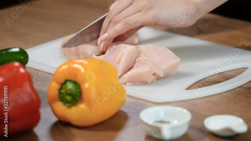 Close-up woman cuts chicken fillet with a ceramic knife on a wooden Board. photo