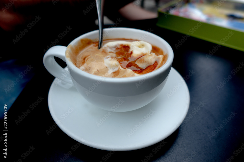 White Cup of Italian coffee-based dessert Affogato coffee with dessert spoon in table. Form of a scoop of vanilla gelato or ice cream topped or drowned with a shot of hot espresso. White Cup of Italian coffee-based dessert Affogato coffee with dessert spoon in table. Form of a scoop of vanilla gelato or ice cream topped or drowned with a shot of hot espresso.