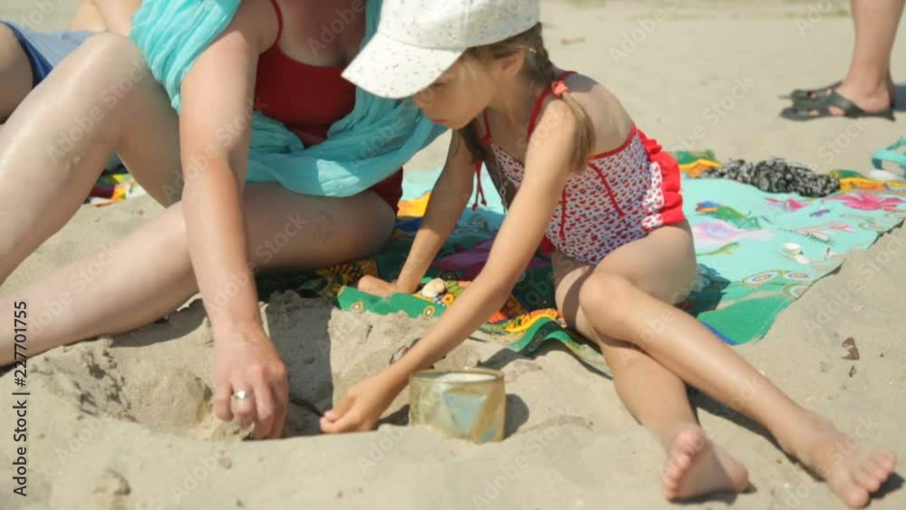 Woman and child playing with sand on beach Woman and child playing with sand on beach