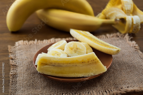 Flesh of ripe banana, cut into pieces in a round plate, wooden background.