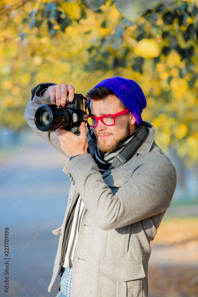 Man with camera and in glasses with hat in autumn season alley Man with camera and in glasses with hat in autumn season alley