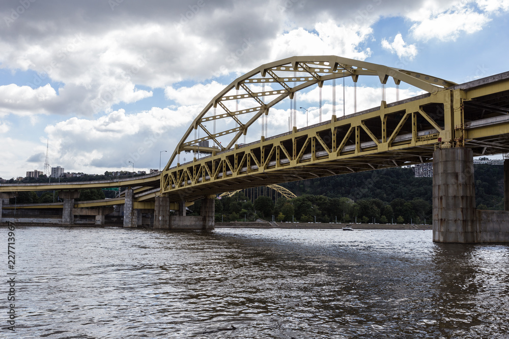 Yellow bridge crossing large river into urban area
