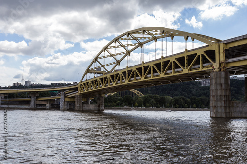 Yellow bridge crossing large river into urban area © Richard