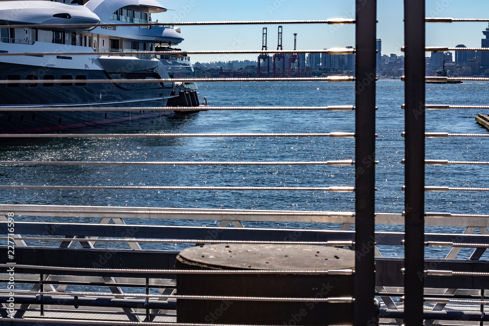 Looking through a guardrail at a docked yacht on a sunny day.