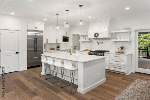 beautiful kitchen in new luxury home with island, pendant lights, hardwood floors, and stainless steel appliances photo
