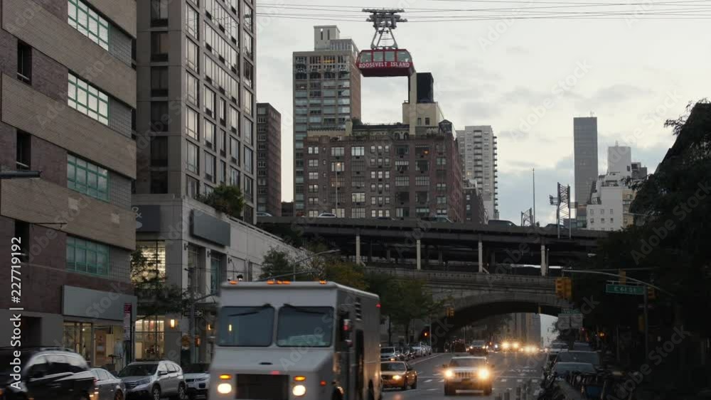 An evening establishing shot of traffic on 1st Avenue in Manhattan as the Roosevelt Tramway travels overhead in the distance. An evening establishing shot of traffic on 1st Avenue in Manhattan as the Roosevelt Tramway travels overhead in the distance.