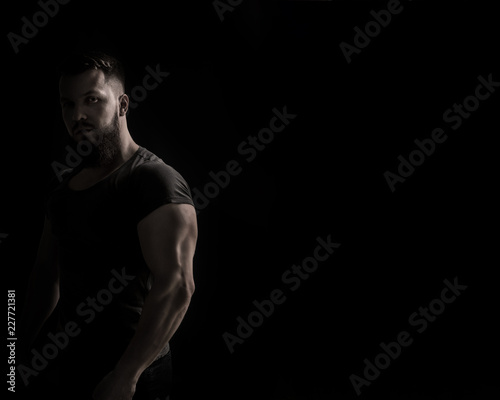 Bodybuilder portrait. Muscular man in a tight-fitting T-shirt. Dramatic portrait in unsaturated colors.