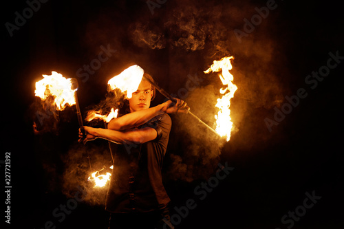Fire show. Fire dancer juggles with two Staff. Night performance. Dramatic portrait. Fire and smoke. photo