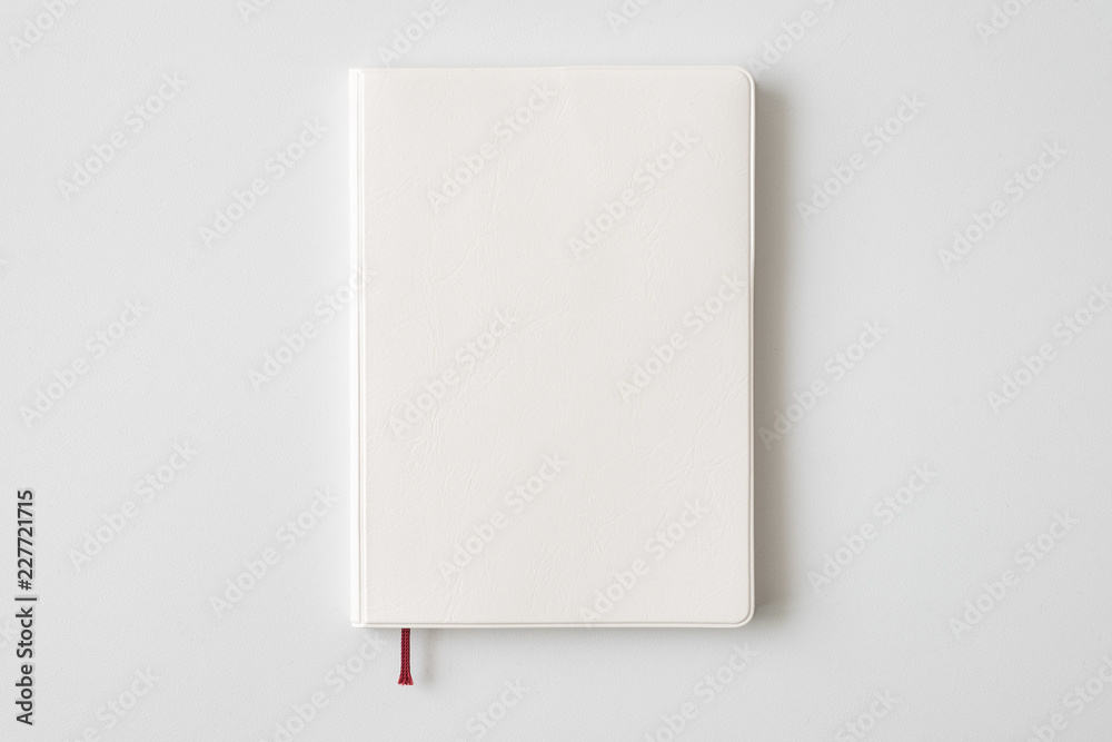 Top view of closed blank white leather cover notebook on white desk background with copy space
