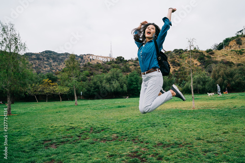 traveler jumping and raising her hands in the sky