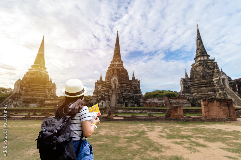 Tourist women with Carrying a backpack Viewing poster, About the temple in Ayutthaya At  Phra Si Sanphet 3 Pagoda Temple.Concept travel in relax..