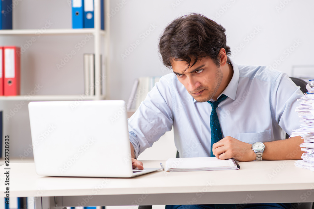 Overloaded busy employee with too much work and paperwork Overloaded busy employee with too much work and paperwork