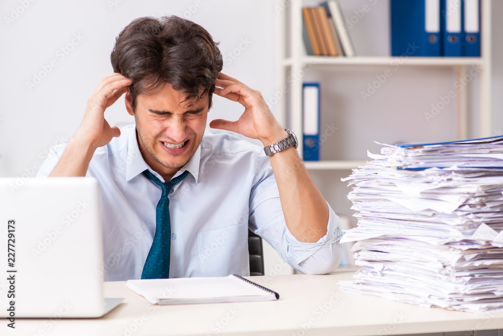 Overloaded busy employee with too much work and paperwork Overloaded busy employee with too much work and paperwork