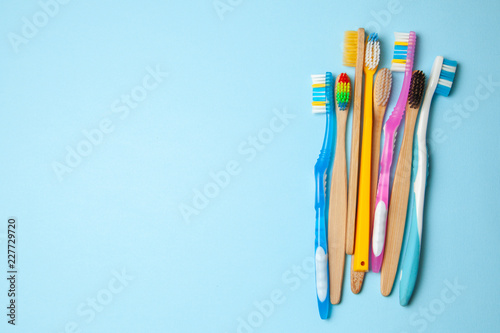 Many colored toothbrushes on blue background. How to choose toothbrush photo