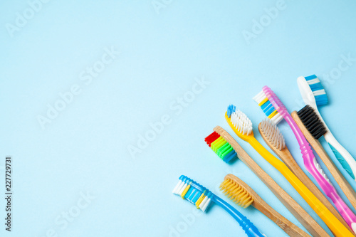 Many colored toothbrushes on blue background. How to choose toothbrush photo