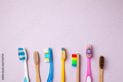 Many colored toothbrushes on purple background. How to choose toothbrush photo