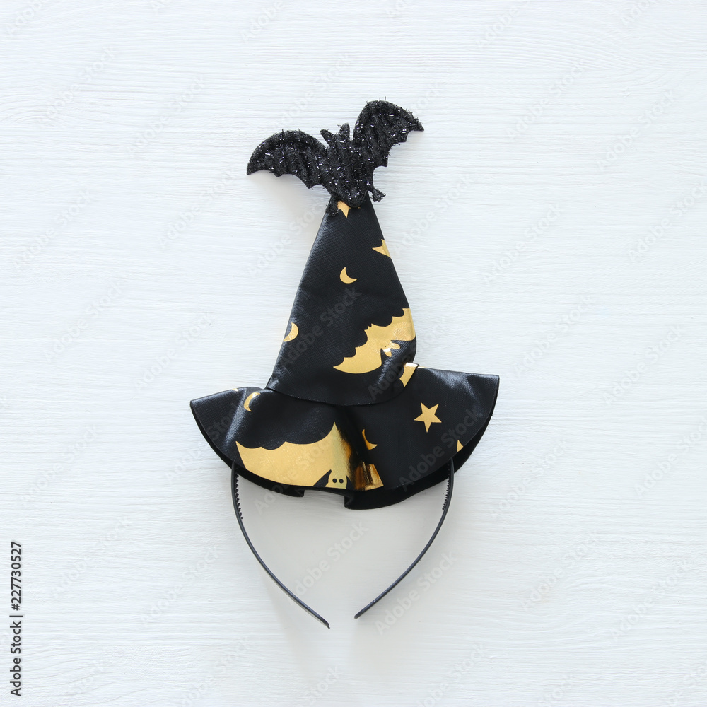 Fototapeta premium Halloween holiday minimal top view image of witch hat over white wooden background.