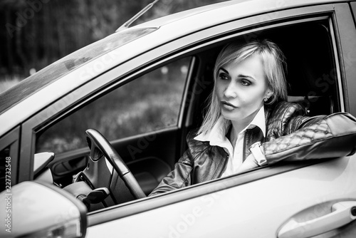 European mature elegant woman and car, lady driving automobile, outdoors portrait. Middle age woman driving on road, trip on beautiful autumn day. Concept of women and auto  