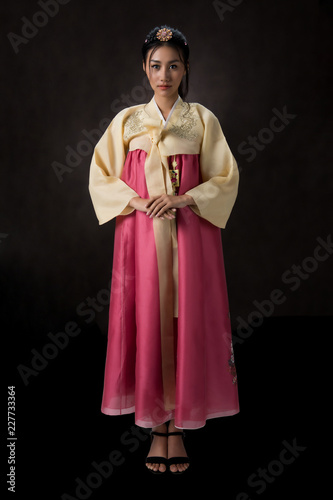 Beautiful Korean girl in Hanbok dress. Looks adorable and elegant. standing front of black background.