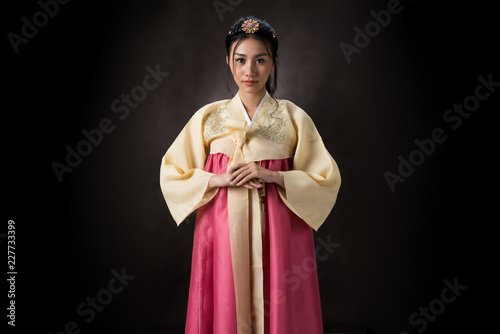 Beautiful Korean girl in Hanbok dress. Looks adorable and elegant. standing front of black background.
