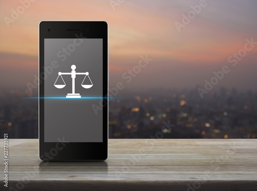 Obraz na plátne Law flat icon on modern smart mobile phone screen on wooden table over blur of c