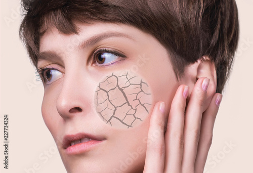 Fotografie Woman face covered with cracked earth texture- symbol of dry skin