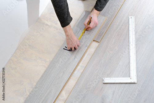DIY, repair, building and home concept - close up of male hands lying parquet floor board/laminate flooring