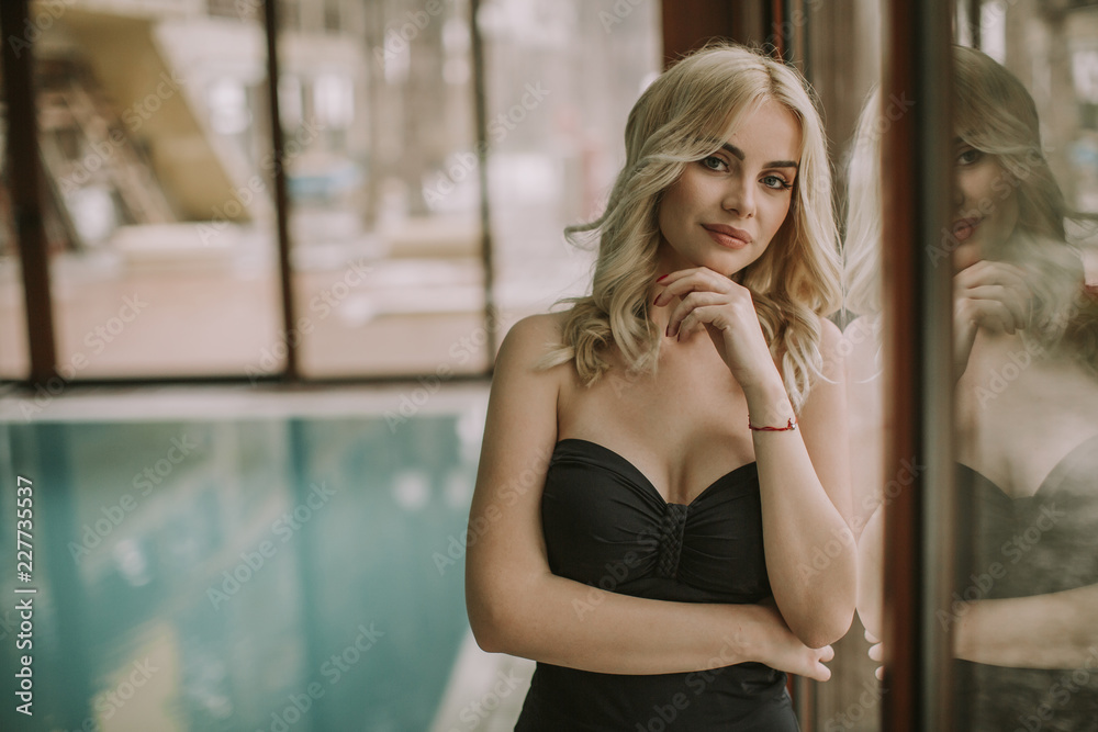 Young woman standing by the swimming pool Young woman standing by the swimming pool