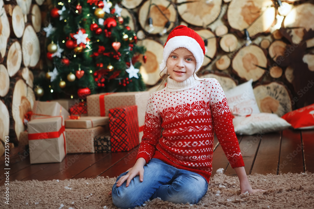 Boy in Christmas hats are lying and laughing on the rug near the New Year tree in the background of tree cuts. Boy in Christmas hats are lying and laughing on the rug near the New Year tree in the background of tree cuts.