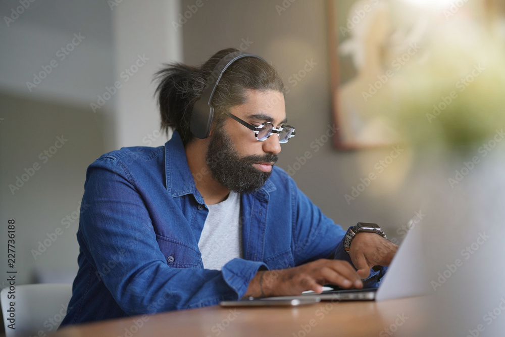 Obraz premium Hipster guy using smartphone and bluetooth headset