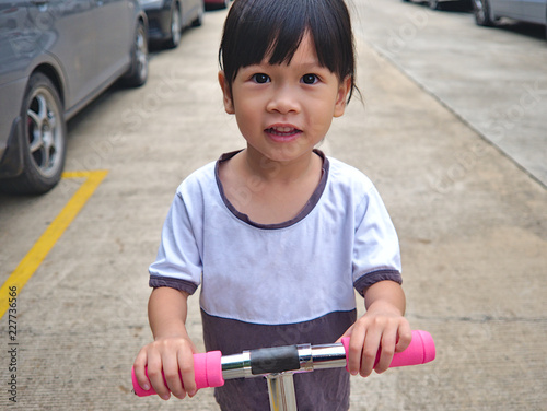 Wallpaper Mural Little Asian kid playing scooter on the public road without safety helmet. Torontodigital.ca