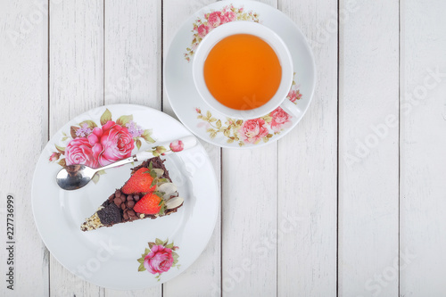 Piece of delicious homemade brownie cake with strawberries and tea  on white table. Selective focus