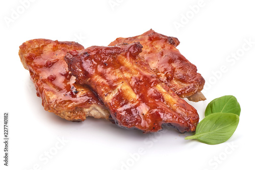 Delicious spicy marinated ribs in a bbq or tomato sauce with basil leaves, isolated on a white background. Close-up.