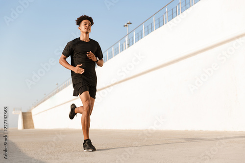 Young guy sportsman outdoors on the beach running.