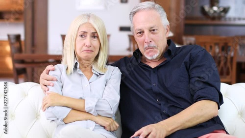 Senior couple watching tv: the woman is crying while the man is laughing, insensitive concept